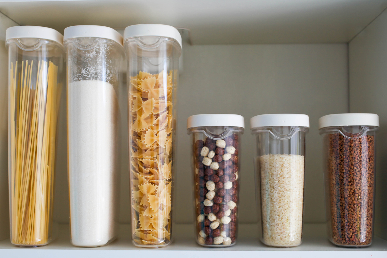 Stocked kitchen pantry with food - pasta, buckwheat, rice and sugar .